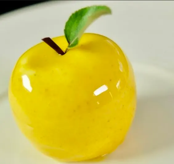 Yellow apple trompe-l'œil entremets with mirror glaze and a single green leaf
