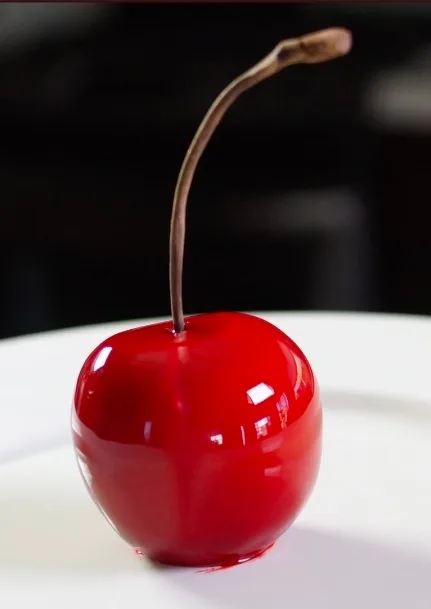 Whole cherry trompe-l'œil entremets with deep red mirror glaze and a natural cherry stem